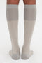 A person wears knee-high, Superfine Rib Socks In Lunar Grey by Victoria Beckham made of 100% cotton with a superfine ribbed texture while standing on a white background.