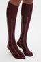 A person wearing Victoria Beckham Superfine Rib Socks In Burgundy against a plain white background.