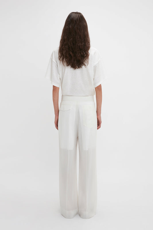 A person is shown from behind, wearing a white t-shirt and contemporary cool Waistband Detail Straight Leg Trouser In White by Victoria Beckham in featherweight wool.
