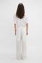 A person is shown from behind, wearing a white t-shirt and contemporary cool Waistband Detail Straight Leg Trouser In White by Victoria Beckham in featherweight wool.