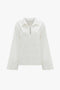 Victoria Beckham's Oversized Embroidered Tunic In Antique White long-sleeve shirt with a collar and a keyhole neckline, crafted from a linen-cotton blend. It features subtle embroidery detailing on the front, reminiscent of Victoria’s runway picks.
