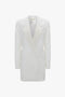 Double-breasted white tuxedo-style long jacket with peaked lapels and two side flap pockets, isolated on a white background from Victoria Beckham's Exclusive Fold Shoulder Detail Dress In Ivory collection.