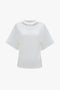 Victoria Beckham's Bonded Jersey Tee In White with crew neck, displayed against a plain background, exuding a sense of modern nonchalance with its relaxed cut.