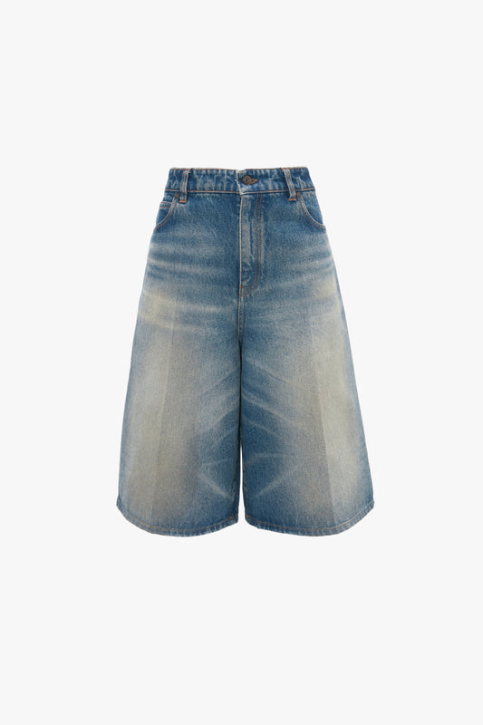 A pair of Victoria Beckham Oversized Bermuda Short In Antique Indigo Wash with a faded front, front button and zipper closure, and two front pockets.
