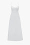 A white, floor-length summer dress with thin spaghetti straps, a fitted bodice, and a flared skirt exudes a bohemian vibe. The Cami Fit And Flare Midi In White by Victoria Beckham perfectly captures this essence.