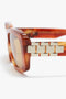 Close-up of a pair of Chain Detail Rectangular Frame Sunglasses In Striped Blonde Havana by Victoria Beckham with gold accents on the temples, focusing on the decorative chain-link detail.