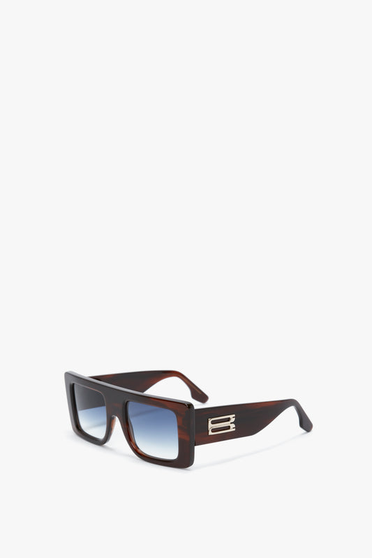Oversized Frame Sunglasses In Brown Horn by Victoria Beckham, with a Brown Horn colourway, dark brown frames, and blue-tinted lenses, featuring metallic accents on the temple arms and displayed on a plain white background.