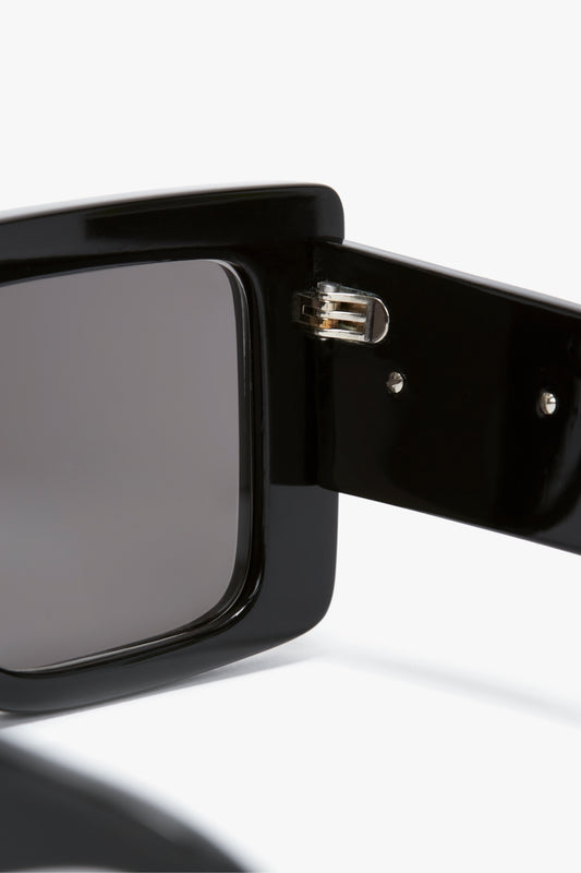 Close-up view of the hinge of a pair of sleek and modern black **Oversized Frame Sunglasses In Black**. The hinge detail showcases the joining mechanism between the bold oversized frame and the temple arm by **Victoria Beckham**.