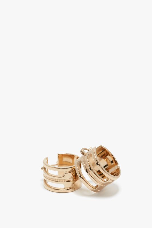A pair of Victoria Beckham Exclusive Frame Hoop Earrings In Gold with a multi-band design, displayed against a plain white background.