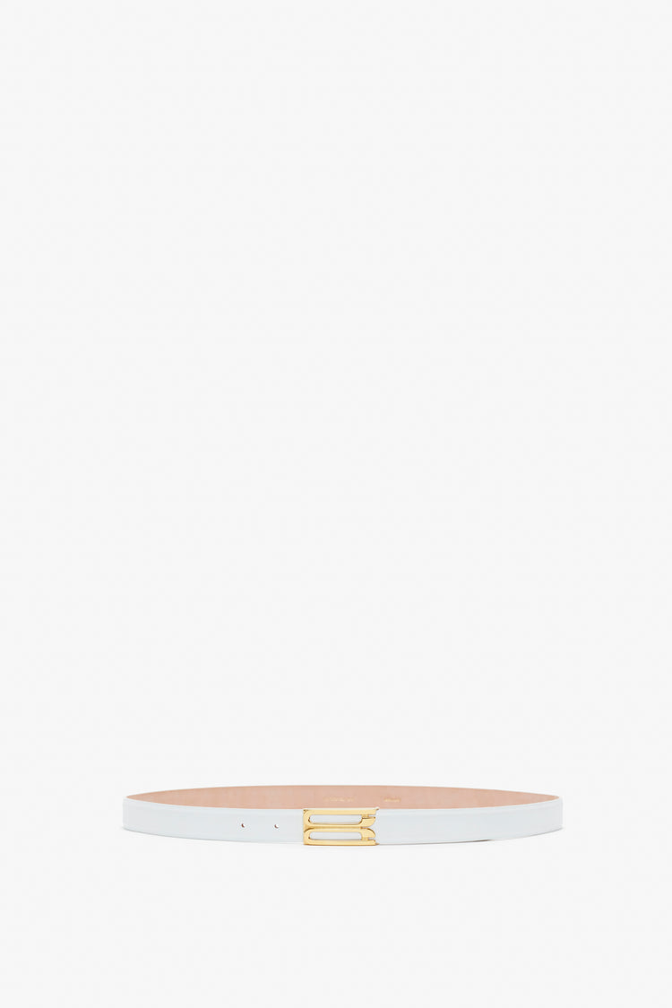 A thin white Frame Belt In White Leather made of smooth calf leather, featuring a small gold buckle, shown against a plain white background by Victoria Beckham.