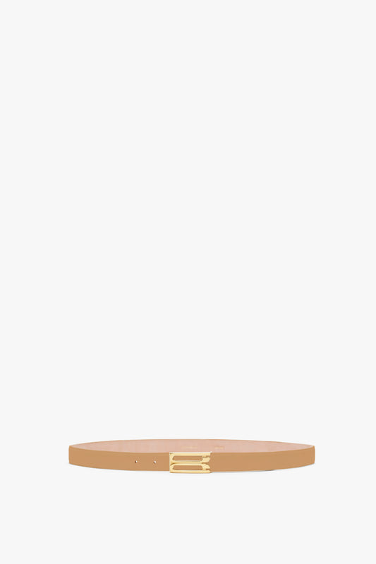 A minimalist thin Victoria Beckham camel calf leather belt with a small golden buckle, displayed against a light gray background.