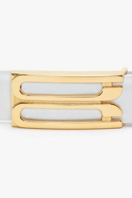 Gold buckle detail on a Victoria Beckham Exclusive Frame Belt In White Leather, featuring a sleek, modern design with two horizontal cutouts.
