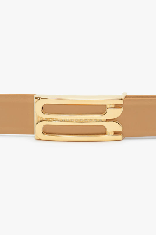 A close-up view of a Victoria Beckham camel leather Frame Belt featuring a polished gold buckle with a unique three-bar design.