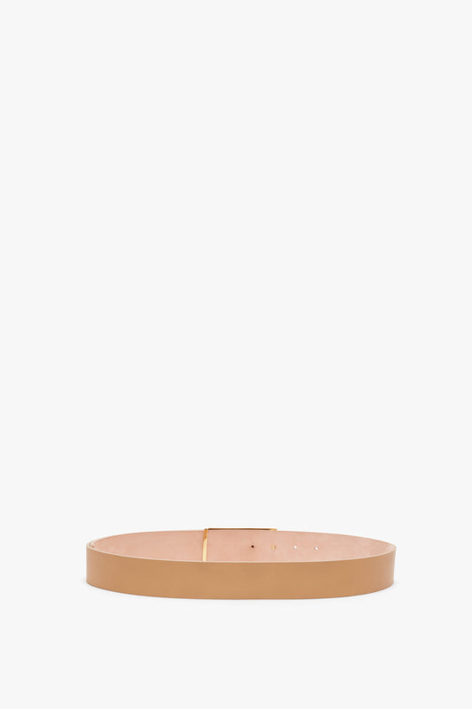 A minimalist Jumbo Frame Belt in Camel Leather with a simple gold buckle, displayed on a white background by Victoria Beckham.