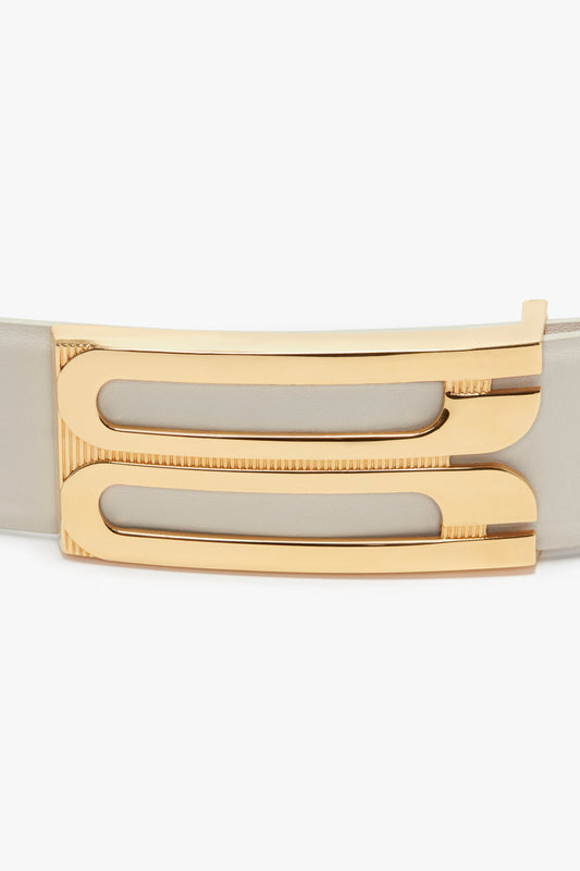 Close-up of a gold metal buckle with a modern geometric design on a contemporary beige calf leather belt, the Jumbo Frame Belt In Latte Leather by Victoria Beckham.