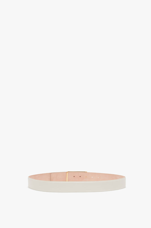 A Jumbo Frame Belt In Latte Leather with a minimal design, featuring gold hardware and a single golden buckle. The interior lining of the contemporary belt is a tan color by Victoria Beckham.
