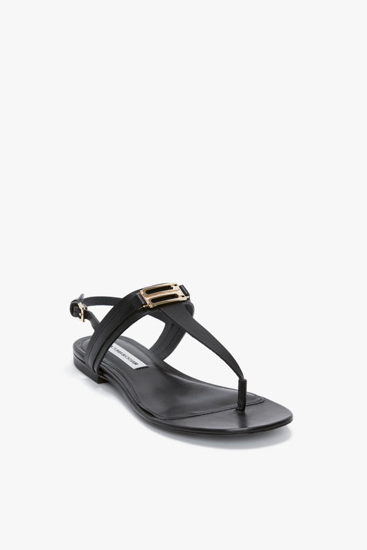 This Flat Chain Sandal In Black Leather by Victoria Beckham features a single black design with a flat sole, crafted from luxurious calfskin leather. It showcases a rectangular metal buckle accent on the strap and a side buckle closure, perfect for sophisticated style in the SS24 collection.