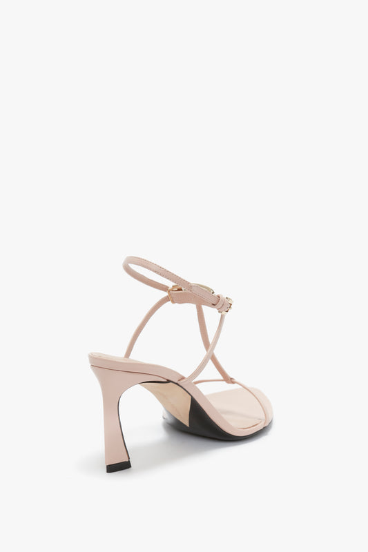 Rear view of a single Victoria Beckham Frame Detail Sandal In Nude Leather with an adjustable ankle strap, V-shaped sculptural heel, and open toe design on a white background.