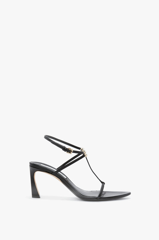 A black high-heeled sandal crafted from nappa leather with a sculptural heel, featuring a thin strap design and an adjustable ankle strap for minimalist detailing, the Frame Detail Sandal In Black Leather by Victoria Beckham.