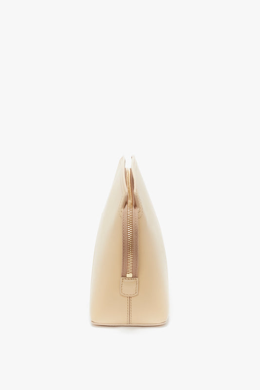 Side view of a versatile beige rectangular bag with a zipper closure running along the top, featuring a structured body ideal for any occasion: the Victoria Clutch Bag In Sesame Leather by Victoria Beckham.