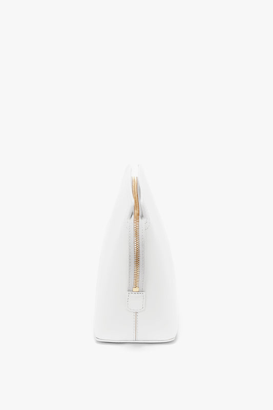 Side view of a white, triangular handbag with a visible gold zipper, featuring a structured design in glossy calf leather. The product is the **Exclusive Victoria Clutch Bag In White Leather** by **Victoria Beckham**.