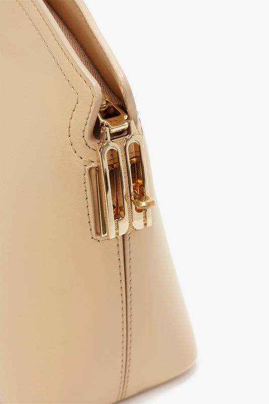 Close-up of a versatile Victoria Clutch Bag In Sesame Leather by Victoria Beckham with a gold-tone clasp and stitching detail on a plain white background.