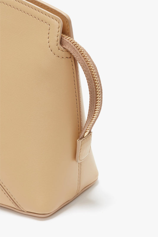 A close-up of the Victoria Beckham Victoria Clutch Bag In Sesame Leather, showcasing its structured body, handle, and seam details against a white background.