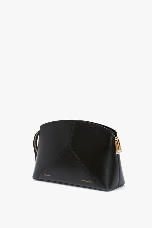A black, structured silhouette handbag in glossy calf leather with gold hardware detailing, featuring "Victoria Beckham" branding near the base against a white background. The product is the Victoria Clutch Bag in Black Leather by Victoria Beckham.