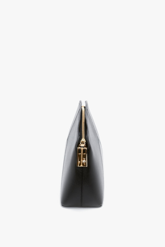 Side view of a glossy calf leather Victoria Clutch Bag In Black Leather by Victoria Beckham with a golden zipper closure, shown against a white background.
