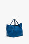 A vibrant blue tote bag made of grained leather, featuring two handles and a simple, minimalist design. 

Replaced: The Victoria Beckham W11 Medium Tote Bag In Vibrant Blue is made of grained leather, featuring two handles and a simple, minimalist design.