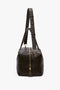 A Medium Gym Bag In Chocolate Brown by Victoria Beckham, with gold zippers and hardware, featuring a shoulder strap and two handles.