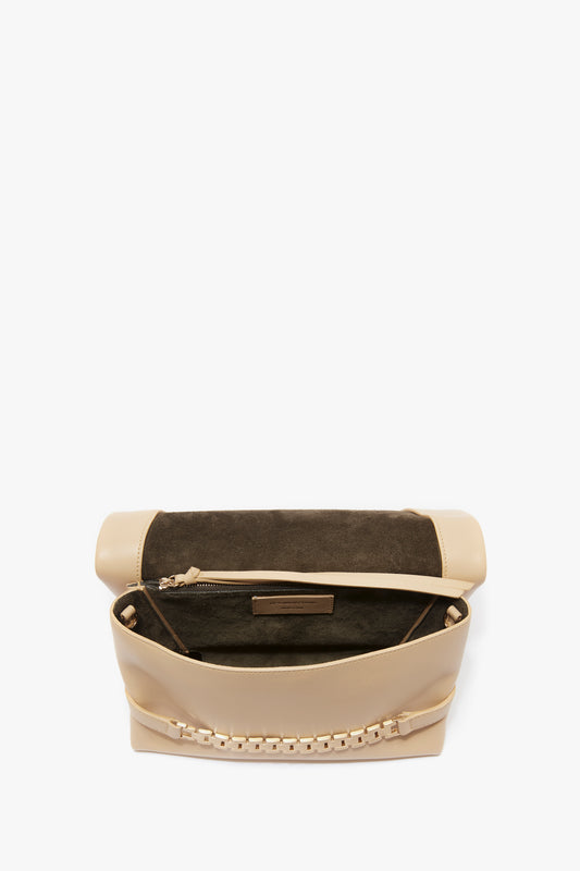 Open Victoria Beckham beige crossbody bag with a studded base and a black fabric interior visible, showing an unzipped inner compartment.