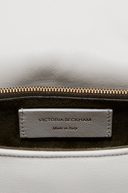 A close-up of an open white leather Puffy Chain Pouch With Strap In White Leather handbag with a visible gold zipper and an interior label that reads "Victoria Beckham, Made in Italy.