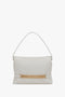 A white Victoria Beckham Puffy Chain Pouch Bag With Strap In White Leather featuring a single strap and a gold chain detail on the front.