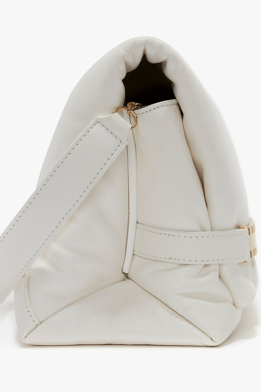 Close-up view of a white leather Victoria Beckham handbag with gold hardware and a wrist strap, featuring a soft, folded design reminiscent of the Puffy Chain Pouch With Strap In White Leather.