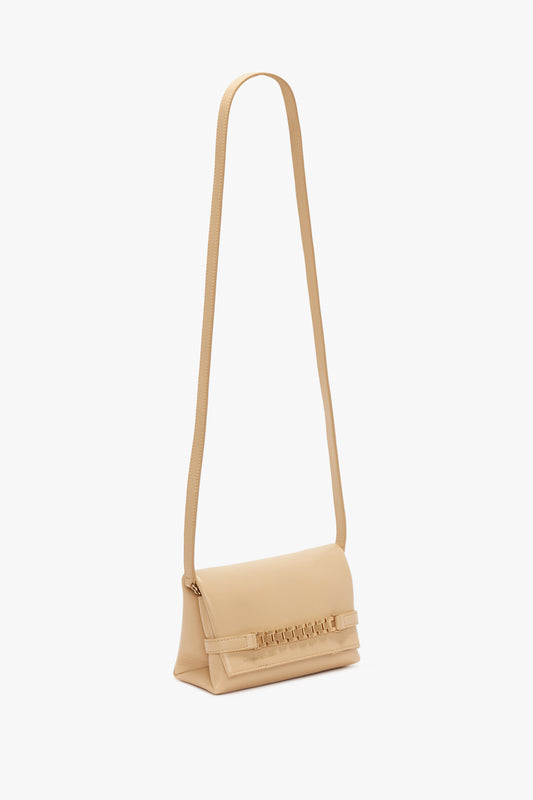 A Mini Pouch With Long Strap In Sesame Leather by Victoria Beckham, featuring a front flap displaying embossed detailing, set against a white background.
