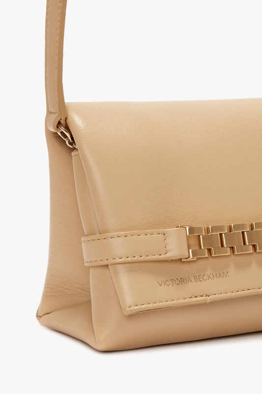 Beige leather crossbody shoulder bag with gold chain detail and designer label 'Victoria Beckham' embossed on the front.