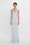 A woman in a Victoria Beckham Exclusive Lace Detail Floor-Length Cami Dress In Ice, standing against a white background.