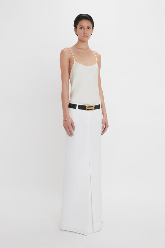 Person wearing an Exclusive Cami Top In Ivory by Victoria Beckham and a long white skirt with a black belt, standing against a plain white background.