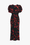 A Gathered Waist Midi Dress In Sci-Fi Black Floral by Victoria Beckham featuring puffed short sleeves and a red floral pattern, gathered at the waist for a fit-and-flare silhouette, extending to mid-calf.