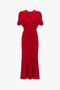 Exclusive Gathered V-Neck Midi Dress In Carmine by Victoria Beckham with short sleeves, a round neckline, and a twisted knot detail at the gathered waist, displayed on a white background.