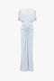 Light blue Exclusive Floor-Length Gathered Dress In Ice by Victoria Beckham with short sleeves and a cinched detail at the waist, creating a waist-defining silhouette. The dress features a round neckline, an elegant open back, and a smooth, flowing skirt for a timeless look.