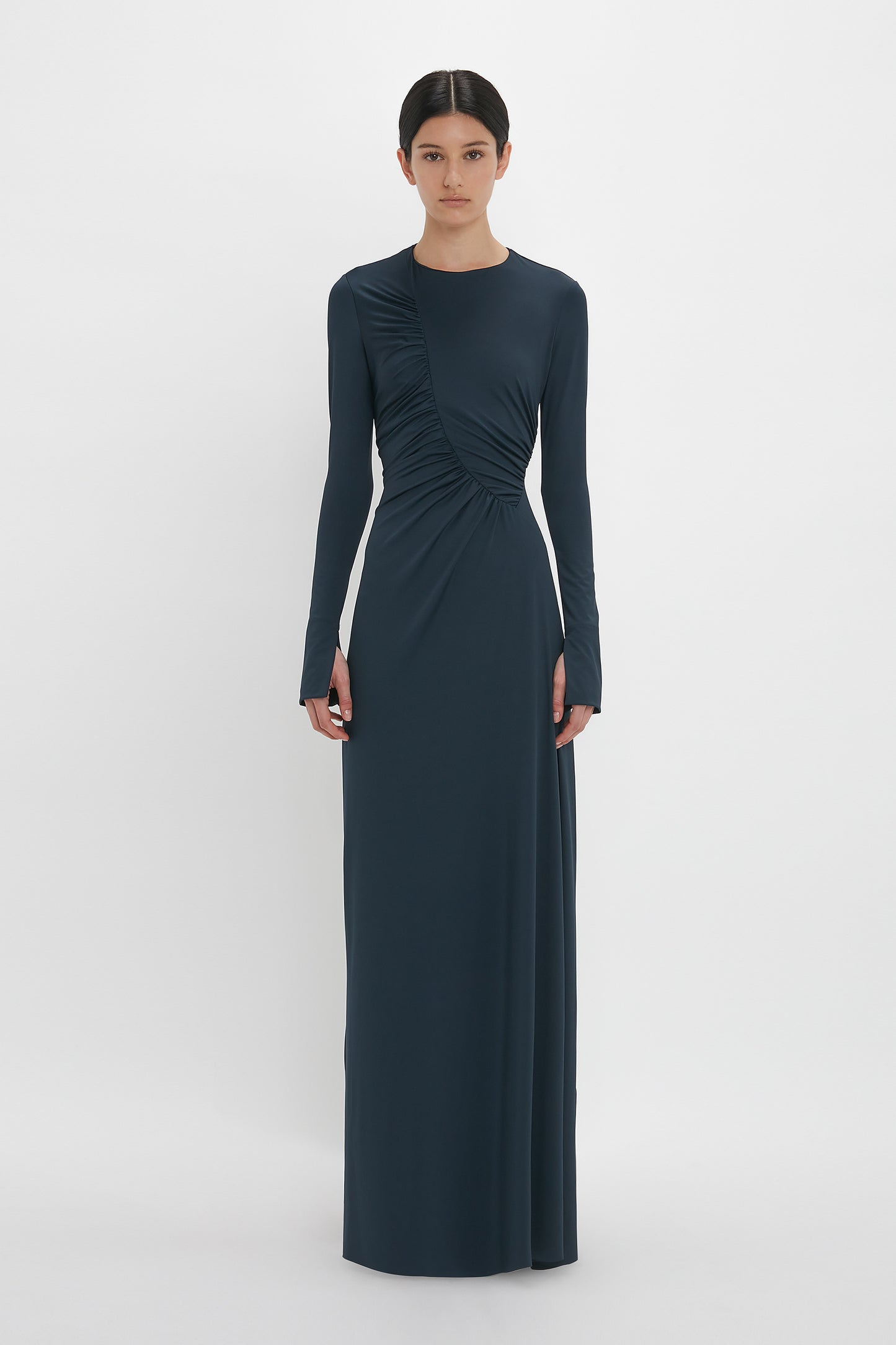 Person wearing a Victoria Beckham Ruched Detail Floor-Length Gown In Midnight with long sleeves, standing against a plain white background.