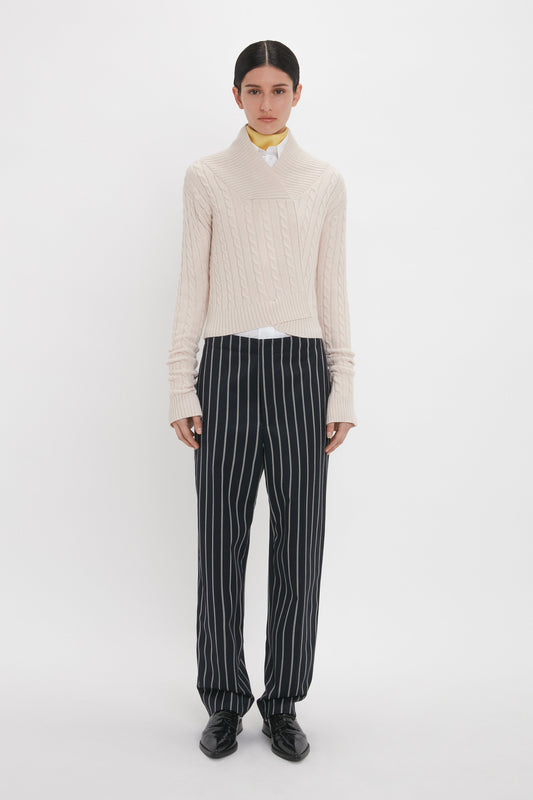 Person wearing a beige knit sweater, white collared shirt, and Victoria Beckham Tapered Leg Trouser In Midnight-White standing against a plain white background.