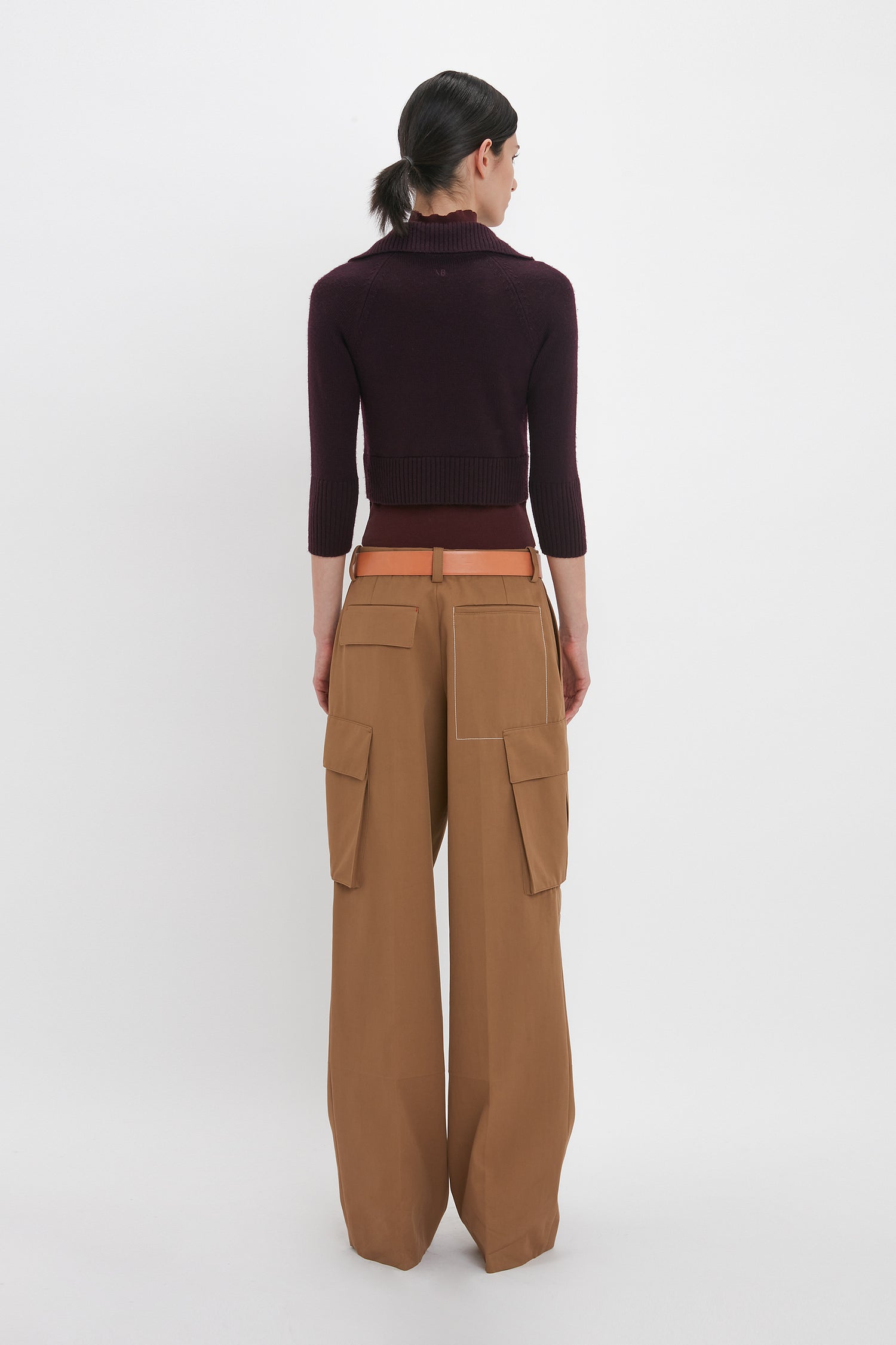 Person standing with their back to the camera, wearing a Victoria Beckham Double Layer Top in Deep Mahogany and tan cargo pants against a plain white background.