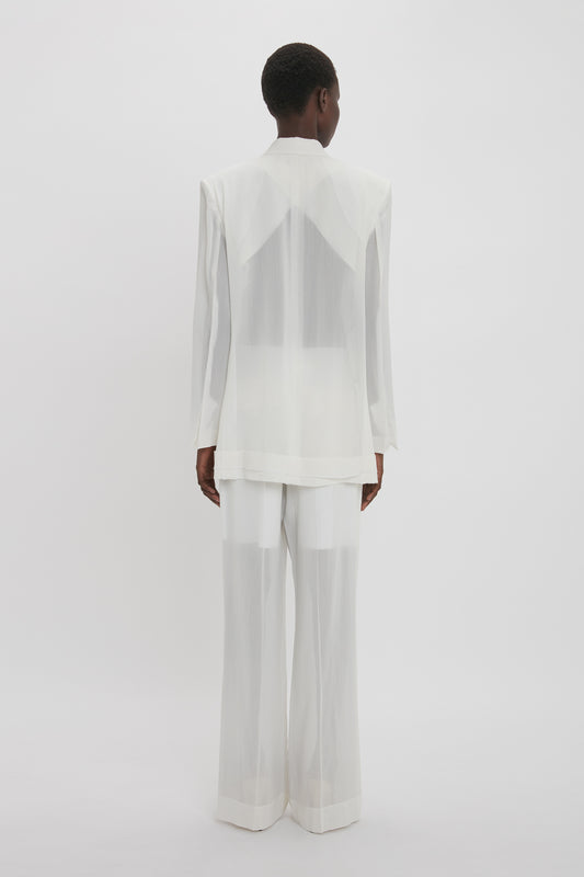 A person is standing in a sheer white, Fold Detail Tailored Jacket In White by Victoria Beckham, shown from the back, against a plain white background.