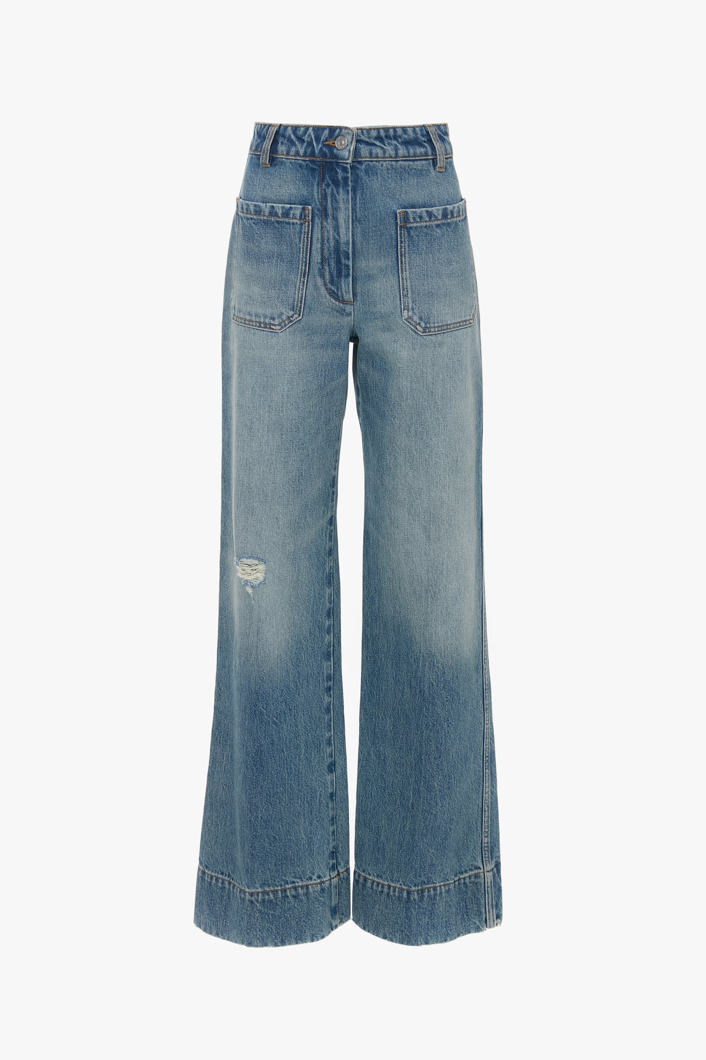 A pair of Alina High Waisted Jean In Worn Blue Wash by Victoria Beckham with seventies-inspired patch pockets, frayed hems, and a small distressed area on the left thigh.