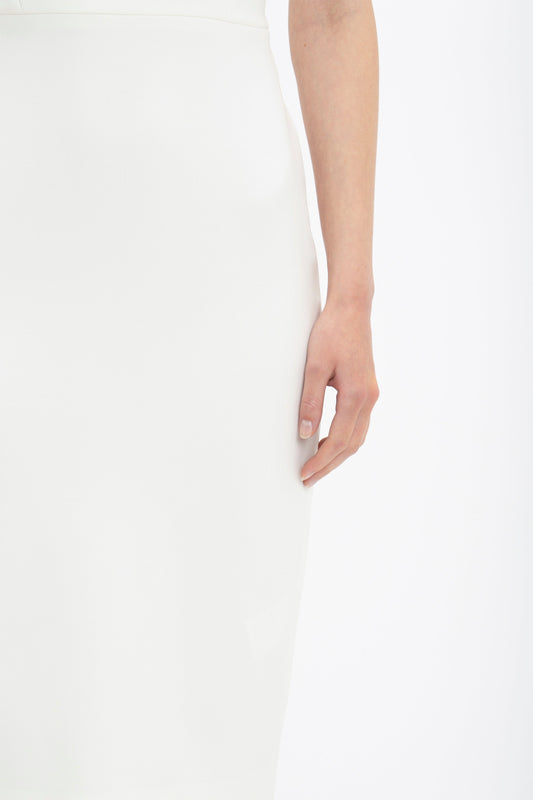 A close-up photo of a person's hand gracefully resting on the side of their elegant Victoria Beckham Fitted T-shirt Dress In Ivory.