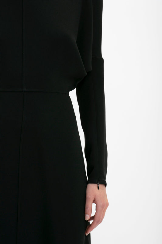 Close-up of a woman in a black Victoria Beckham Dolman Sleeve Midi dress, focusing on her side profile from the waist up, with one hand visible.