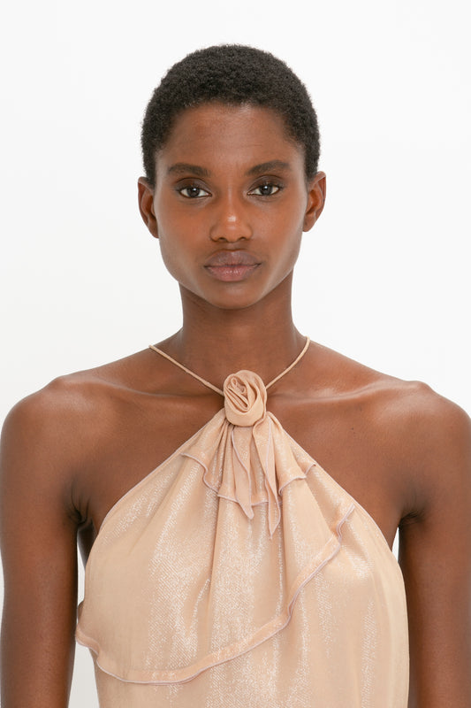 A person with short hair wearing a light-colored, sleeveless Flower Detail Cami Top In Rosewater from Victoria Beckham looks straight ahead against a plain background.